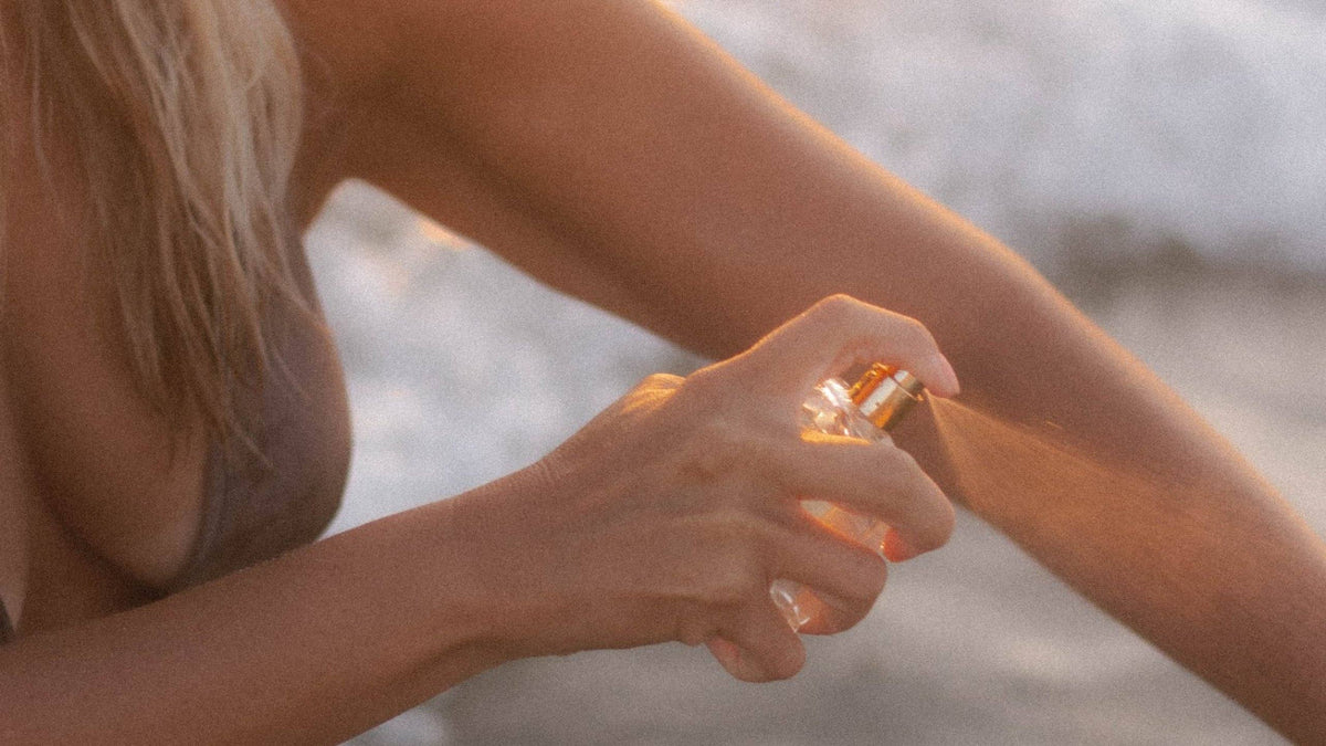 Evelyn Ginossi misting Marine + Vine Tahitian Oil onto her arm in golden light